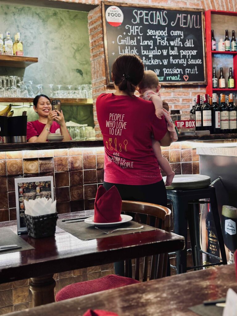 Baby wordt gedragen door personeel in restaurant Hanoi, Vietnam